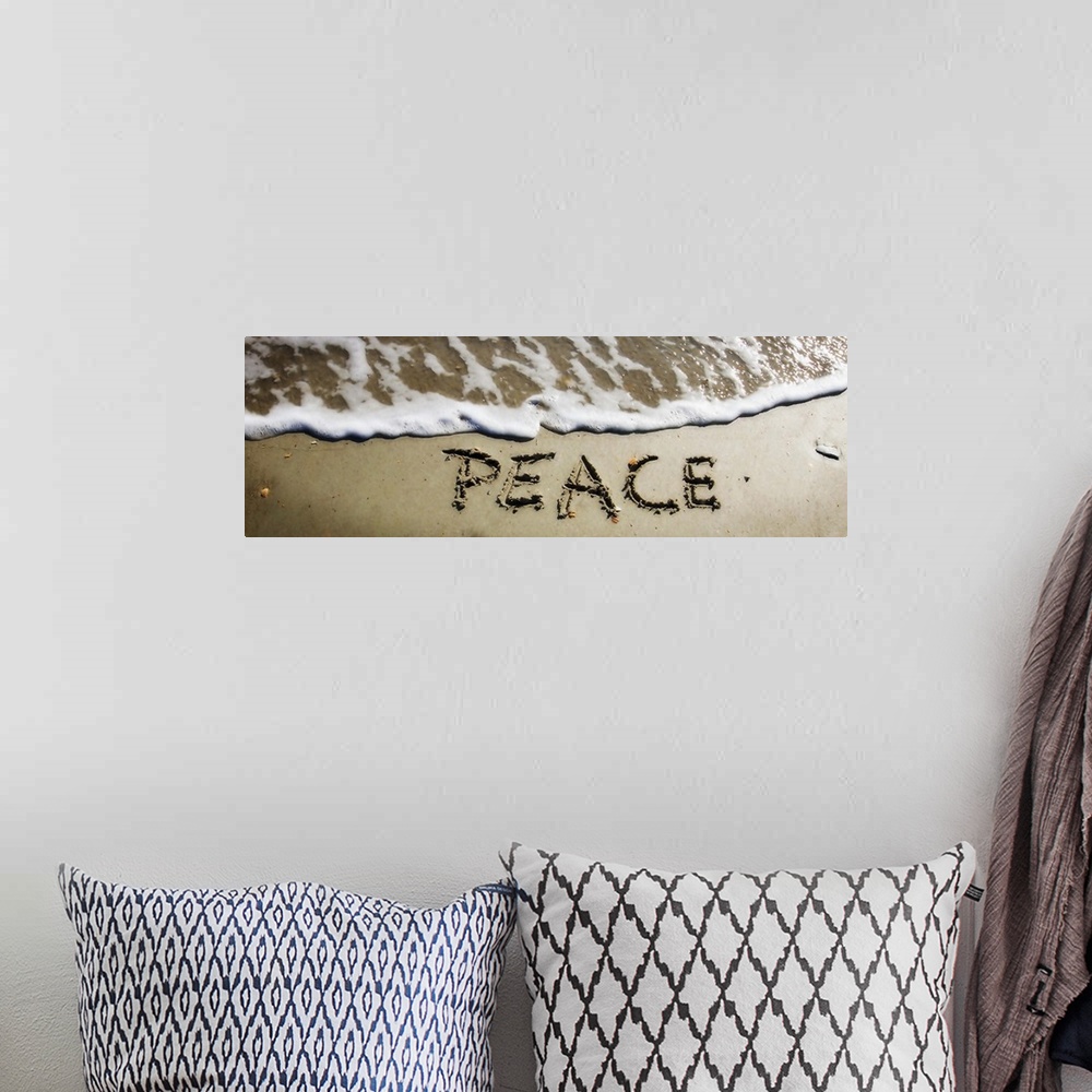 A bohemian room featuring The word "Peace" drawn in the wet sand near ocean water.