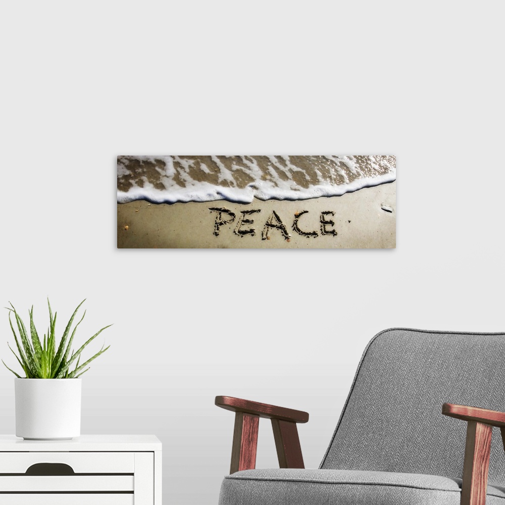 A modern room featuring The word "Peace" drawn in the wet sand near ocean water.