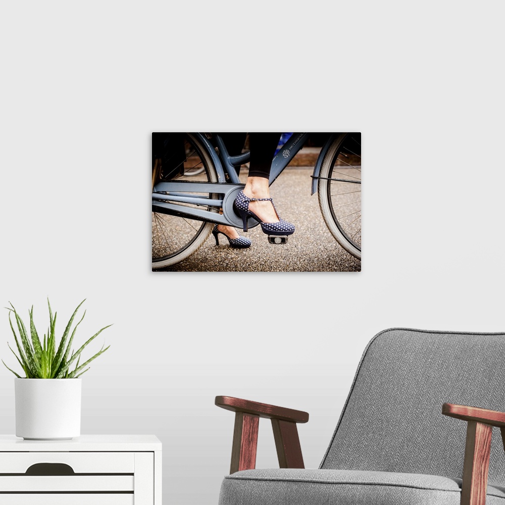 A modern room featuring A woman in dotted high heels stepping onto the a bike pedal.