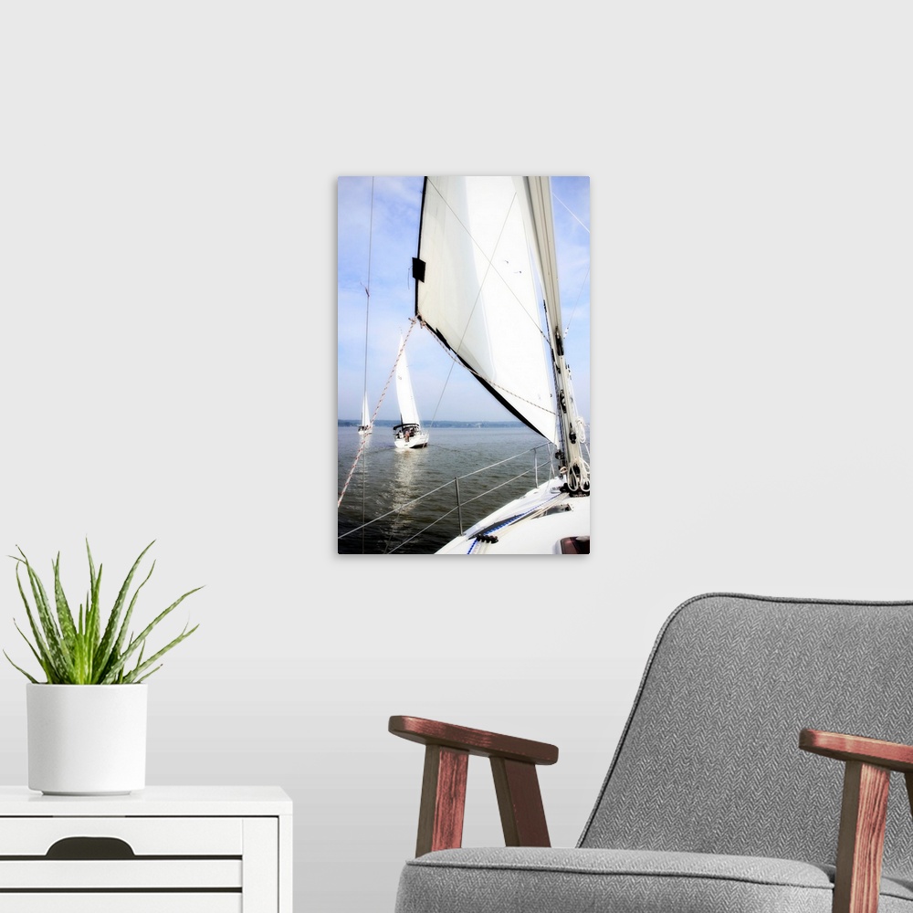 A modern room featuring Big vertical photograph of a sail and the front of a sailboat, looking out toward the water where...
