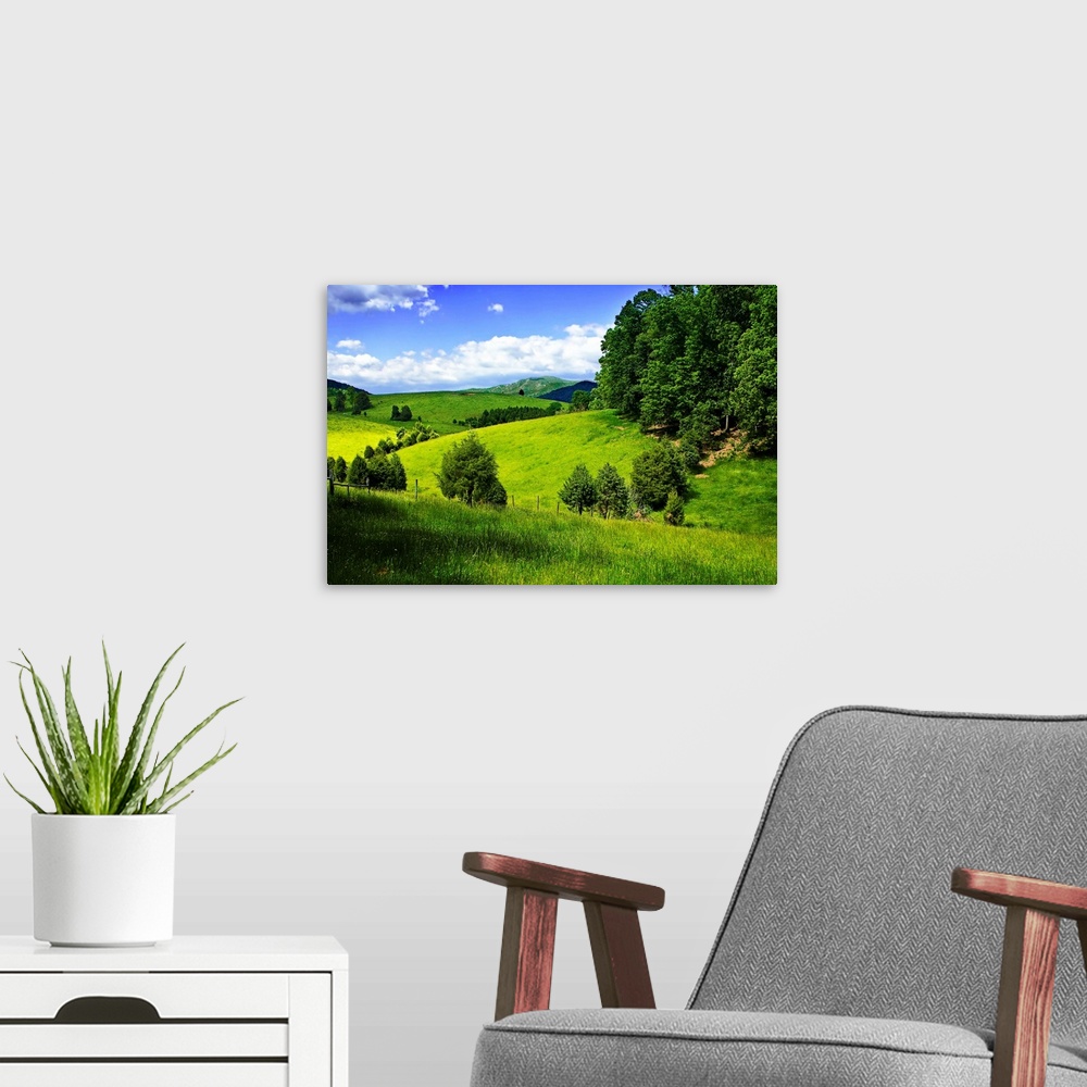 A modern room featuring Verdant hills in the countryside under a bright blue sky.