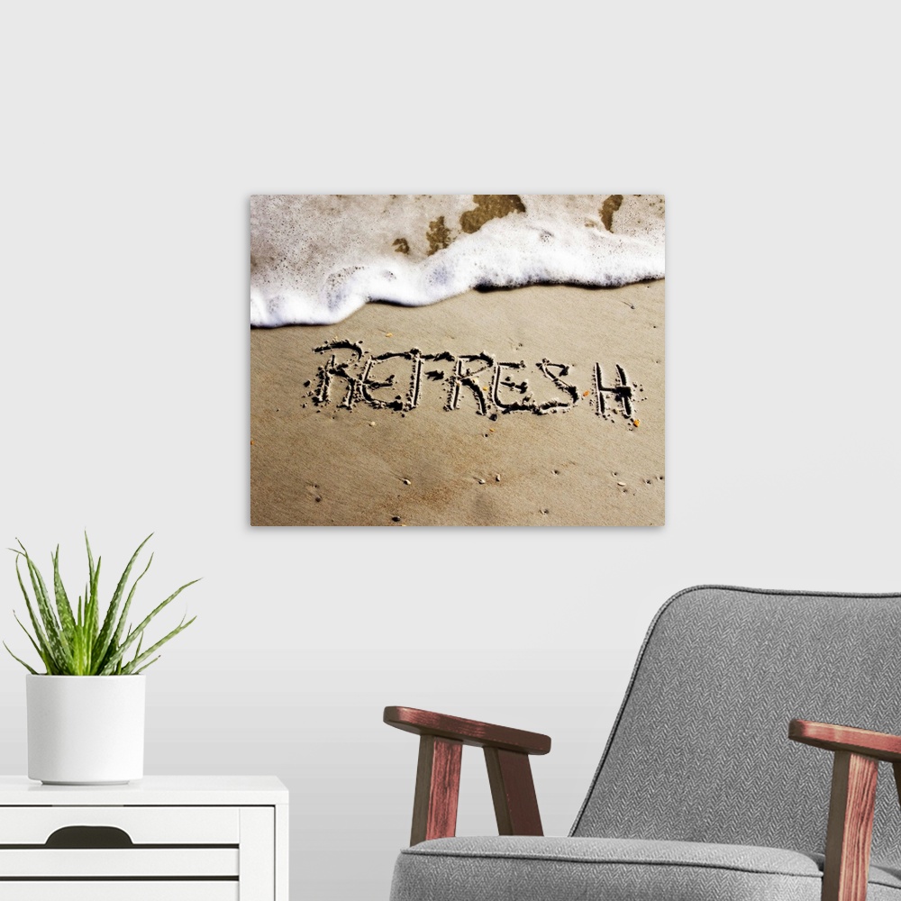 A modern room featuring The word "Refresh" drawn in the sand near the ocean water.