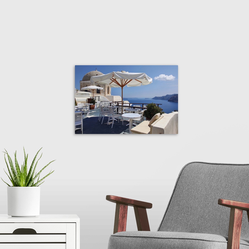 A modern room featuring Open air restaurant on deck with adjacent church overlooking caldera in Santorini, Greece