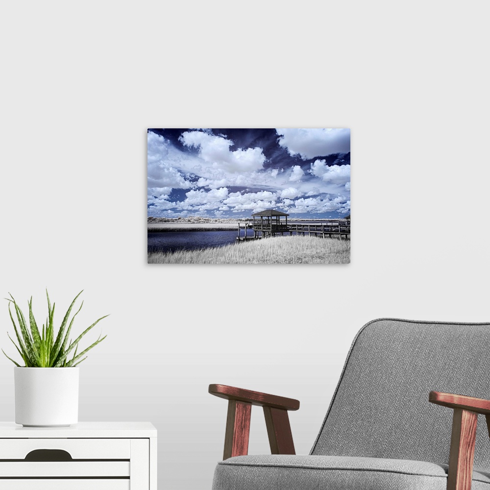 A modern room featuring Cool toned photograph of a dock out to a river flowing through the marsh with beautiful, white, f...