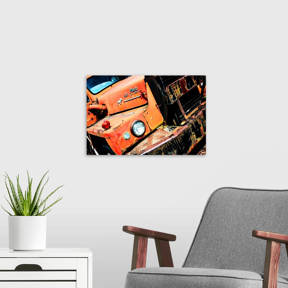 A modern room featuring Photograph of an old, rusted, orange Mack truck from a unique angle.