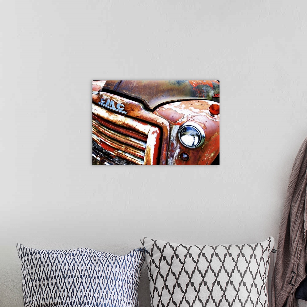 A bohemian room featuring Photograph of the front of an old, rusted, orange GMC truck.