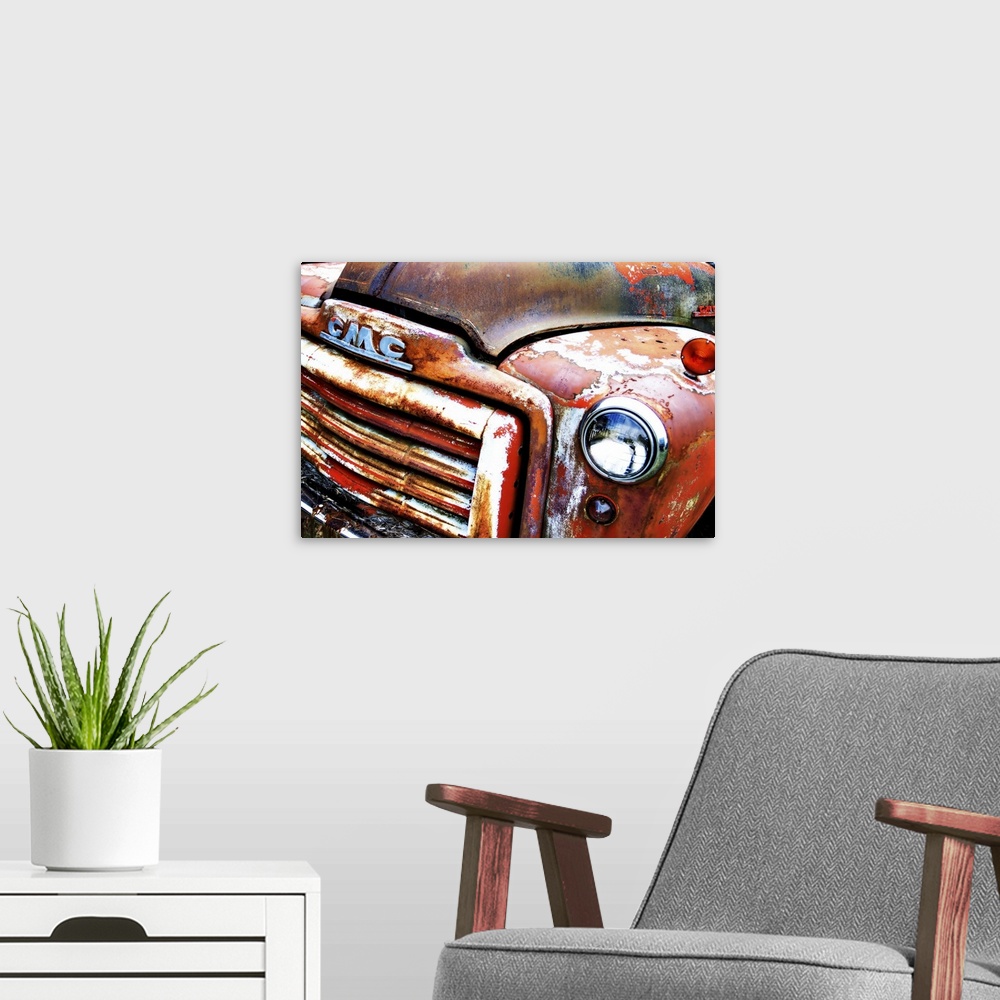 A modern room featuring Photograph of the front of an old, rusted, orange GMC truck.