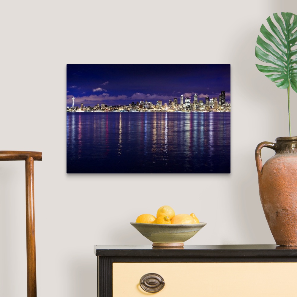 A traditional room featuring Panoramic photograph of cityscape with waterfront at night.  The buildings are lit up and the lig...