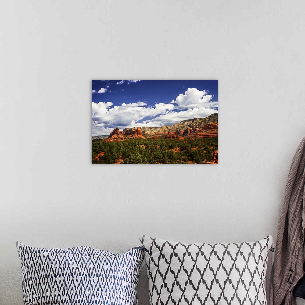 A bohemian room featuring Landscape photograph of rock formations and big white clouds in the blue sky over Sedona, Arizona.
