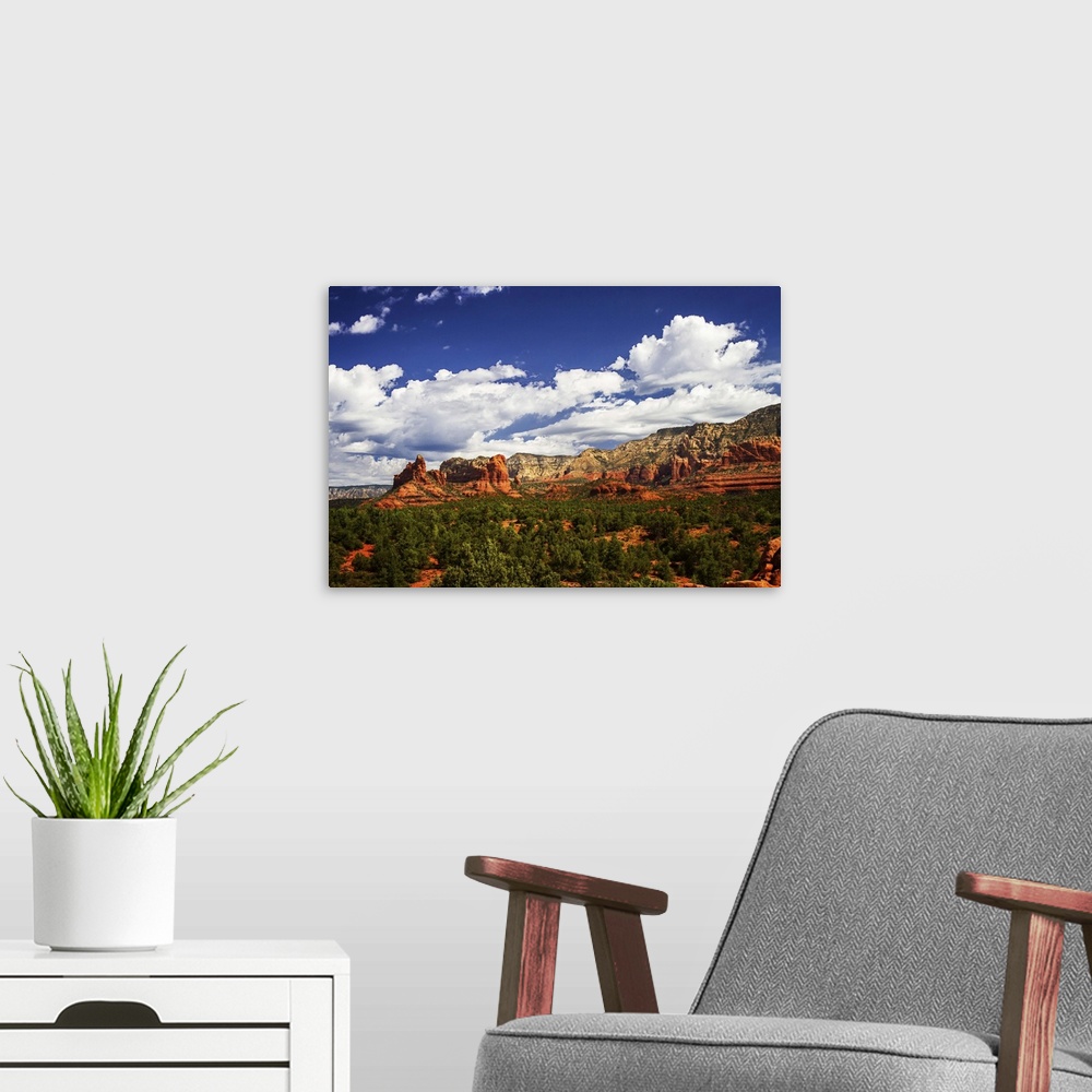 A modern room featuring Landscape photograph of rock formations and big white clouds in the blue sky over Sedona, Arizona.