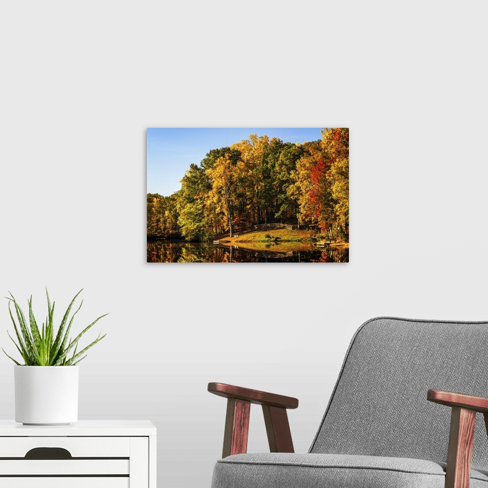 A modern room featuring Landscape photograph of a lake reflecting Autumn trees.