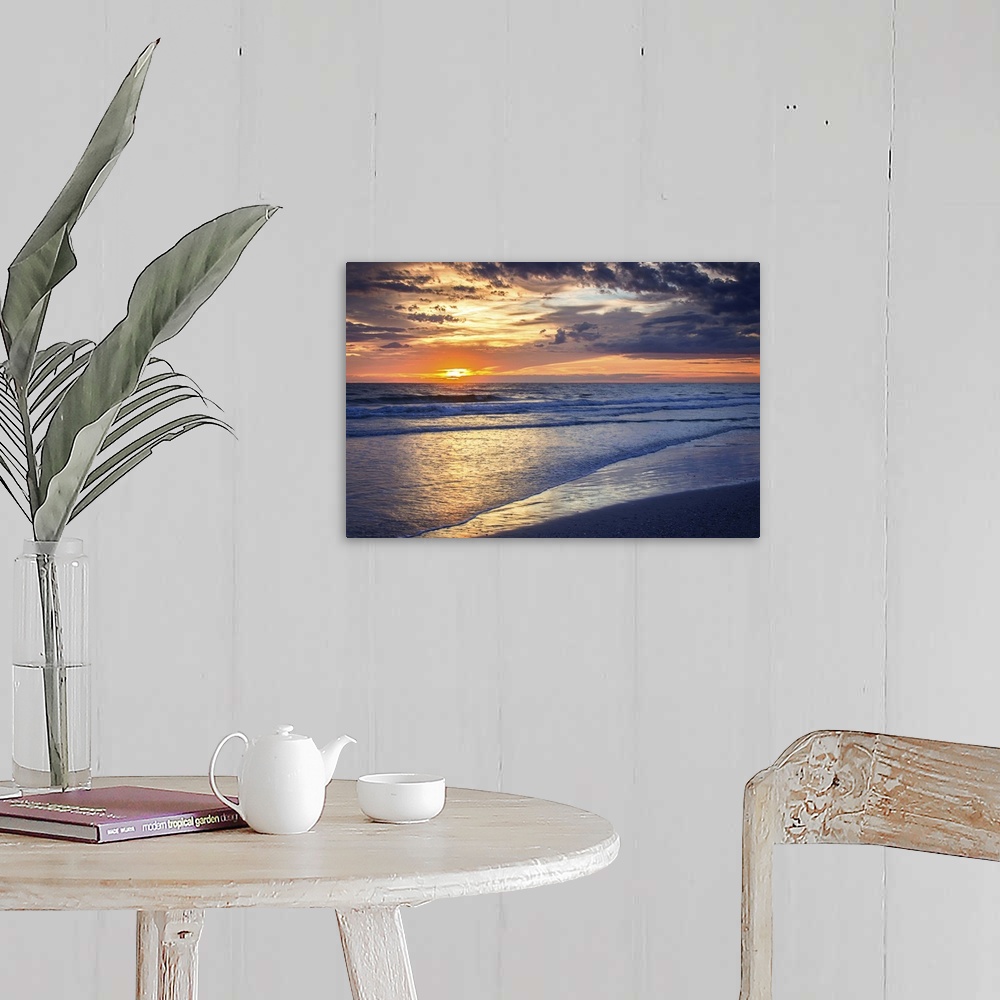 A farmhouse room featuring Cloudy sky at sunrise glowing orange over the beach.