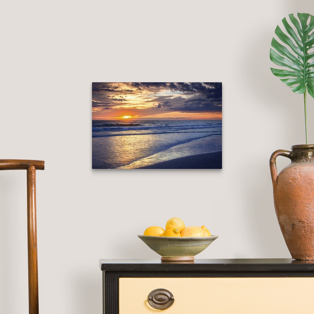 A traditional room featuring Cloudy sky at sunrise glowing orange over the beach.