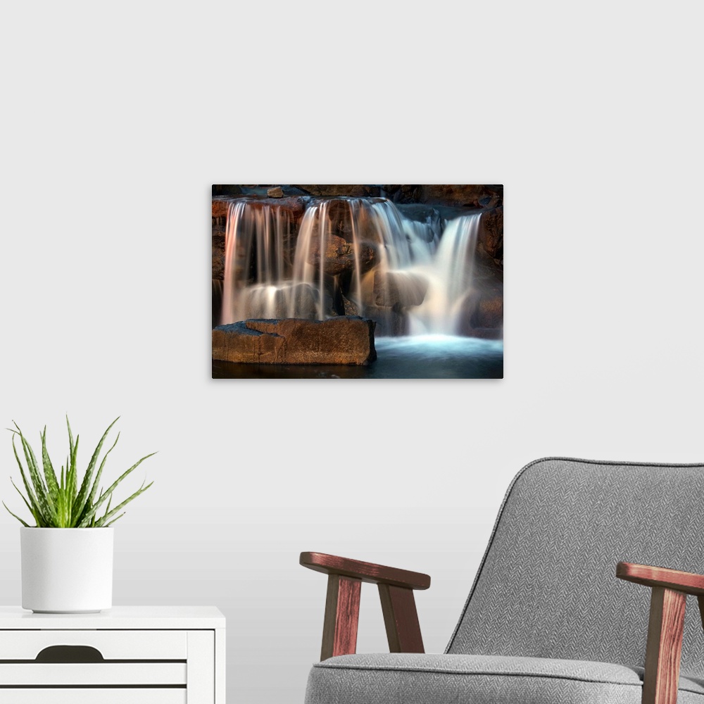 A modern room featuring Long exposure photograph of a waterfall lit with warm light from the sunset.