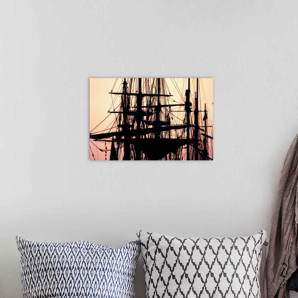 A bohemian room featuring A beautiful picture taken of the tops of ships that are silhouetted by a sunset sky as the backdrop.