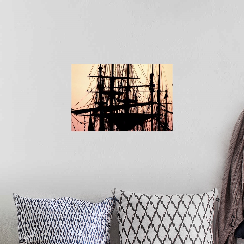 A bohemian room featuring A beautiful picture taken of the tops of ships that are silhouetted by a sunset sky as the backdrop.