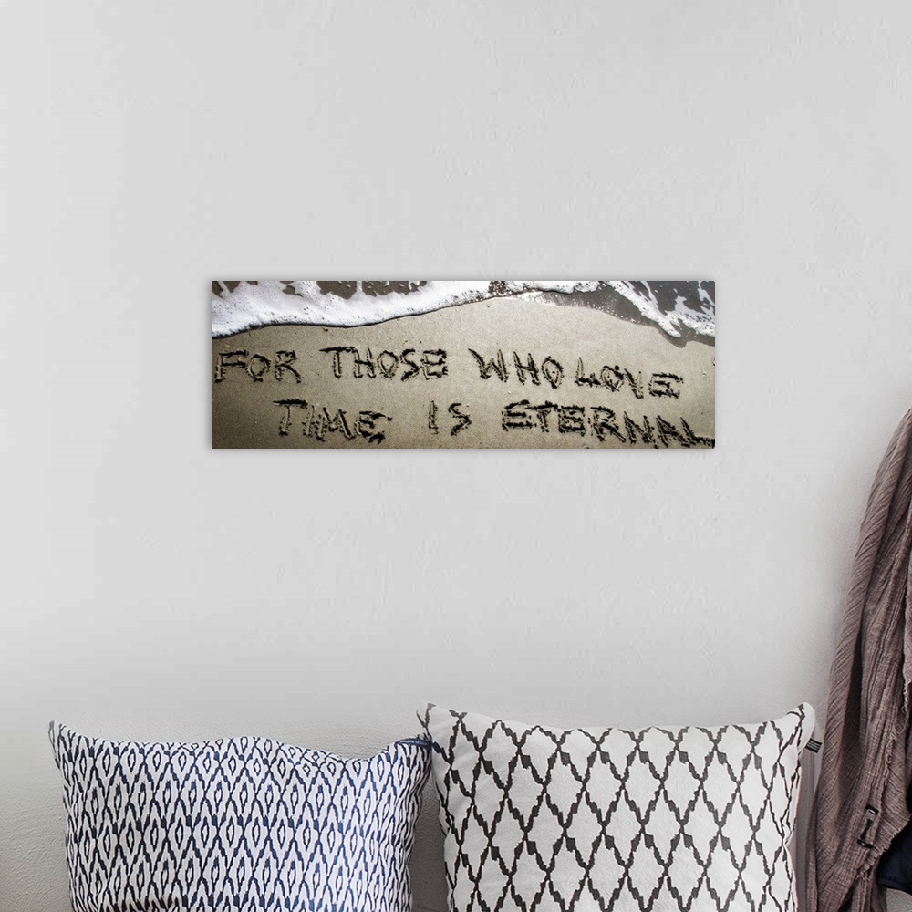 A bohemian room featuring A Bible verse drawn in the sand near the ocean water.