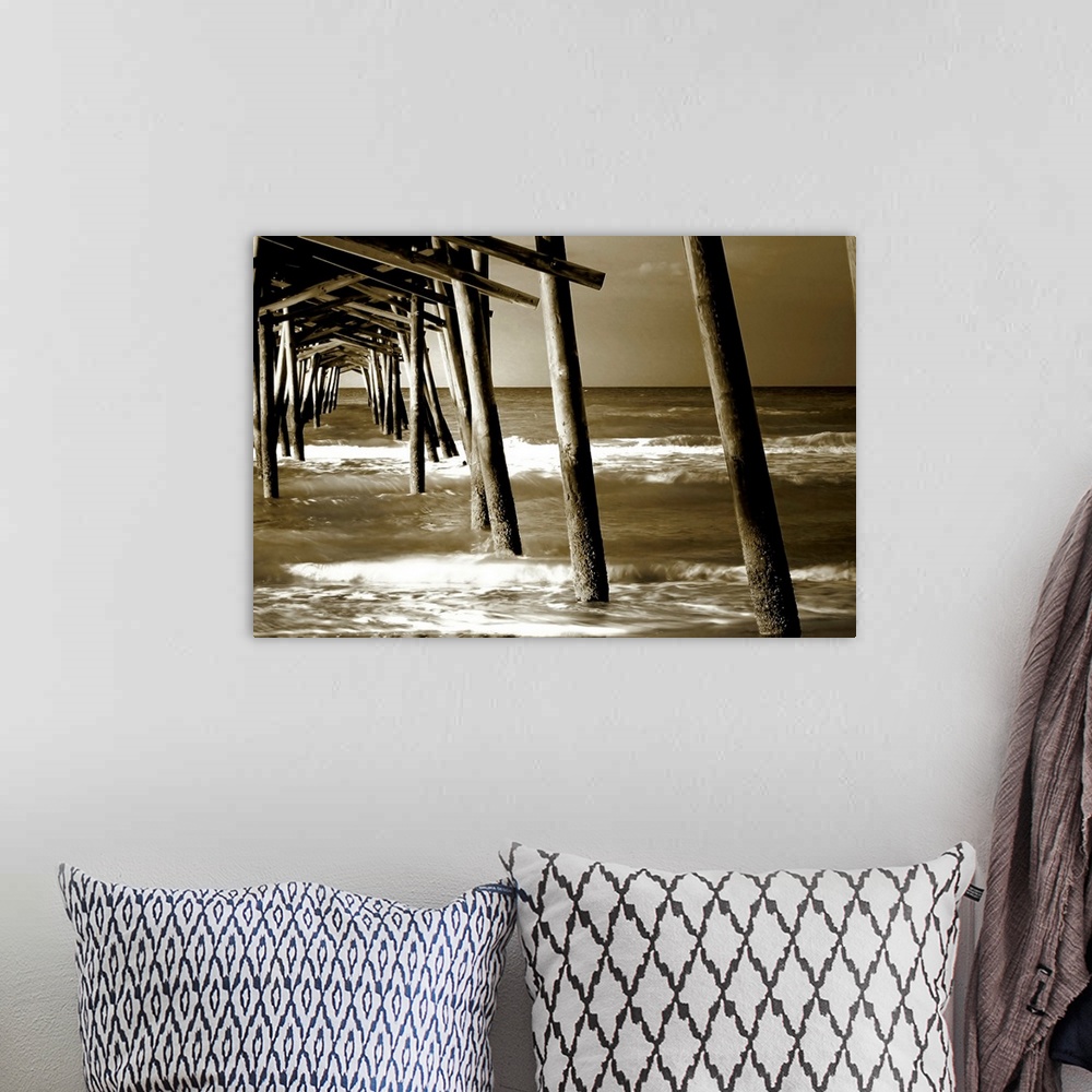 A bohemian room featuring Photograph underneath a wooden pier with waves rolling in.