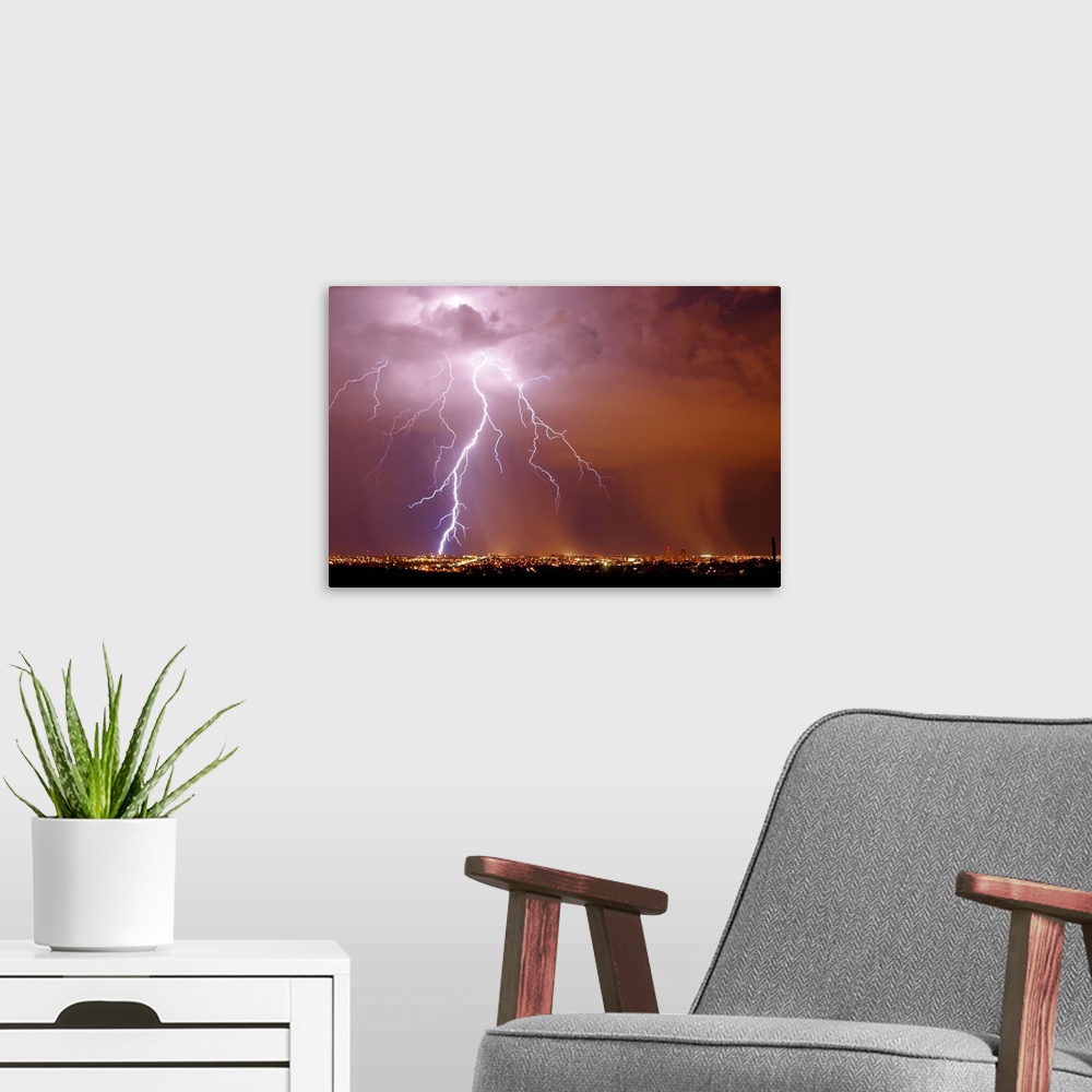 A modern room featuring Photograph of lightning striking in an orange, pink, and purple sky above a city in Arizona.