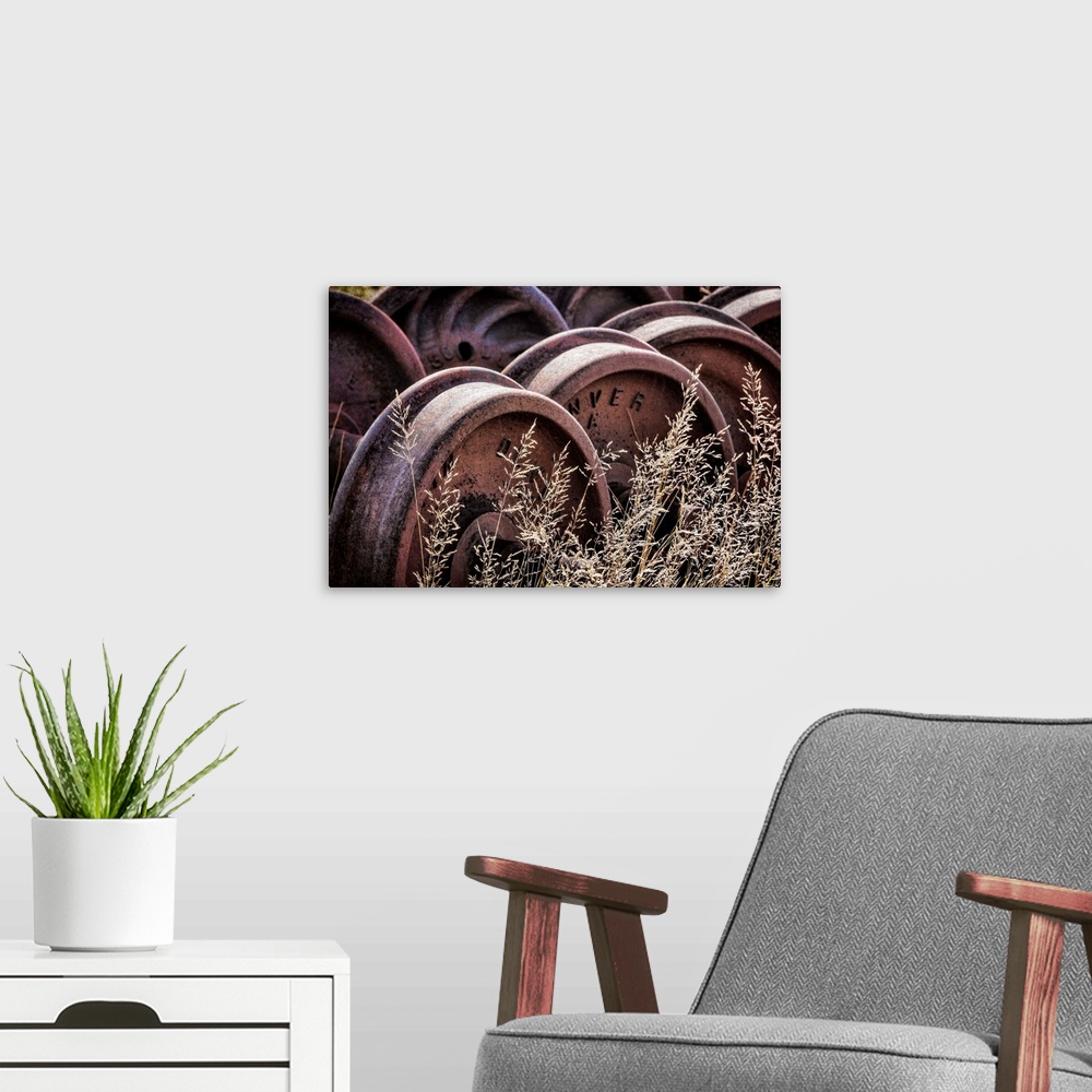 A modern room featuring Photograph of old train wheels in the grass.