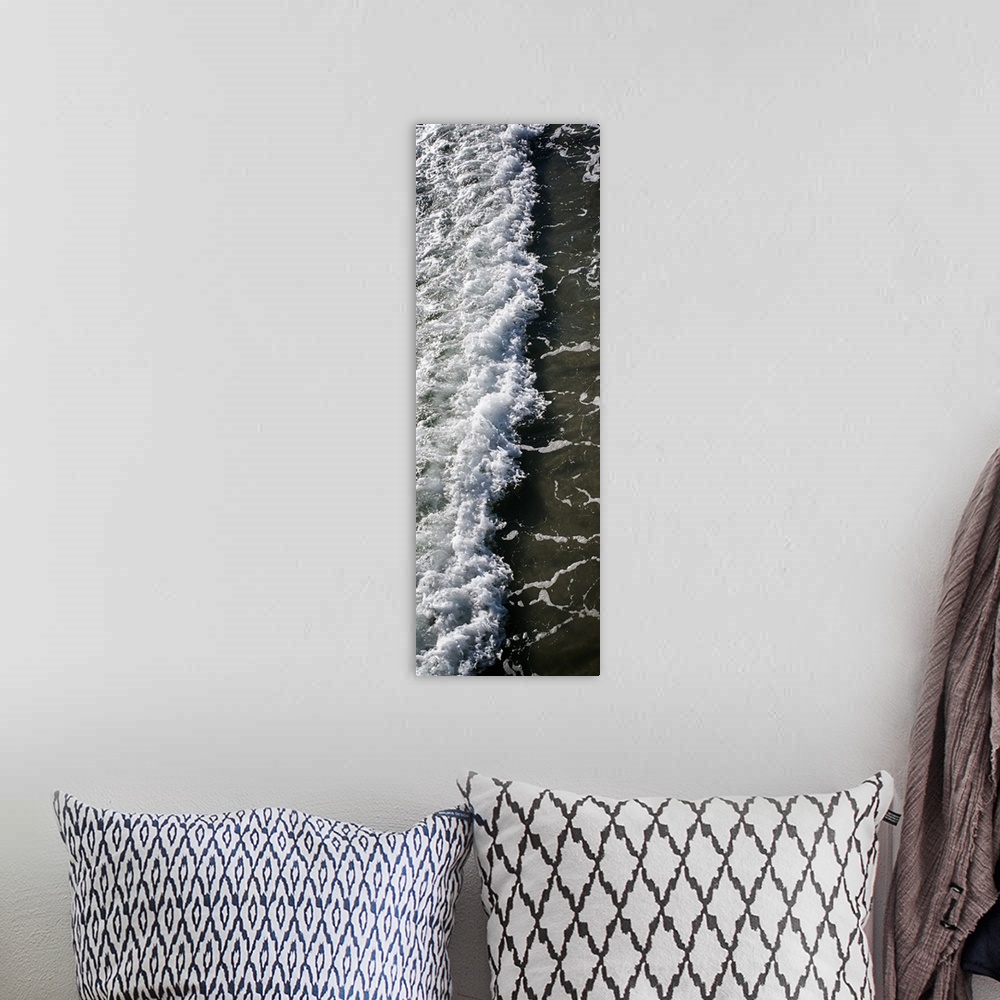 A bohemian room featuring Tall, panoramic photograph of the white water from a crashing wave onto the shore.