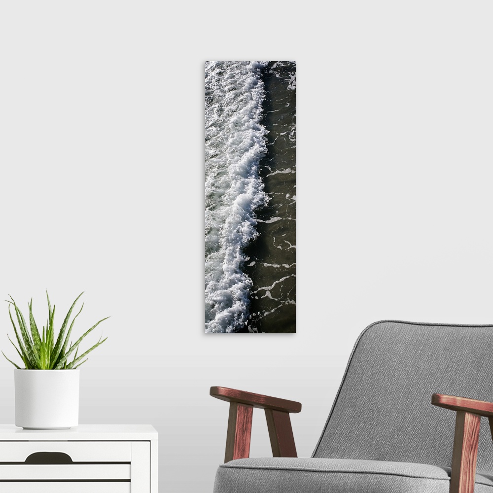 A modern room featuring Tall, panoramic photograph of the white water from a crashing wave onto the shore.