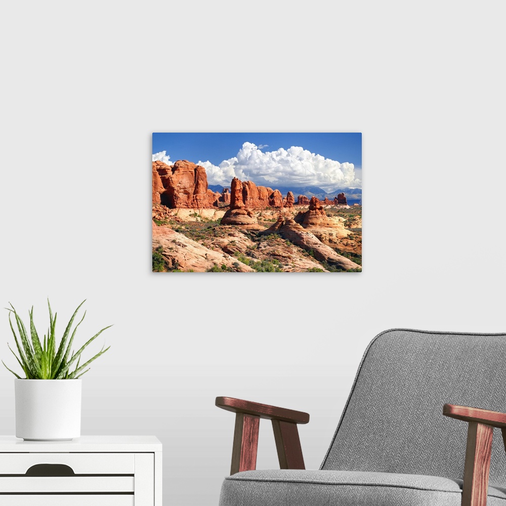 A modern room featuring Landscape photograph of sandstone rock formations in the desert with fluffy white clouds in the sky.