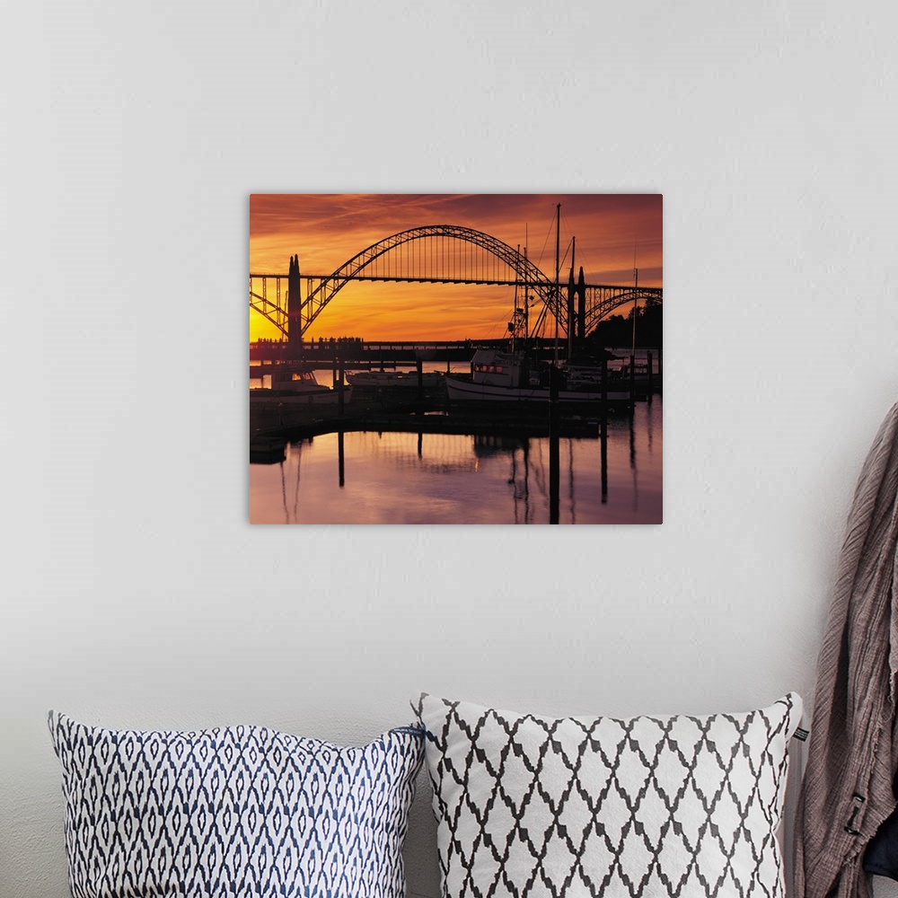 A bohemian room featuring Sunset photograph with silhouetted boats on the Yaquina Bay with a bridge in the background.