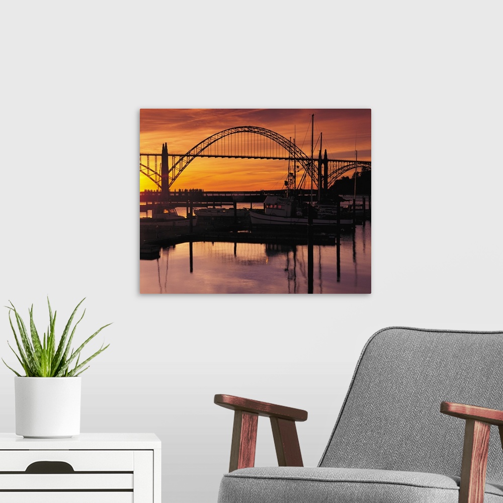 A modern room featuring Sunset photograph with silhouetted boats on the Yaquina Bay with a bridge in the background.