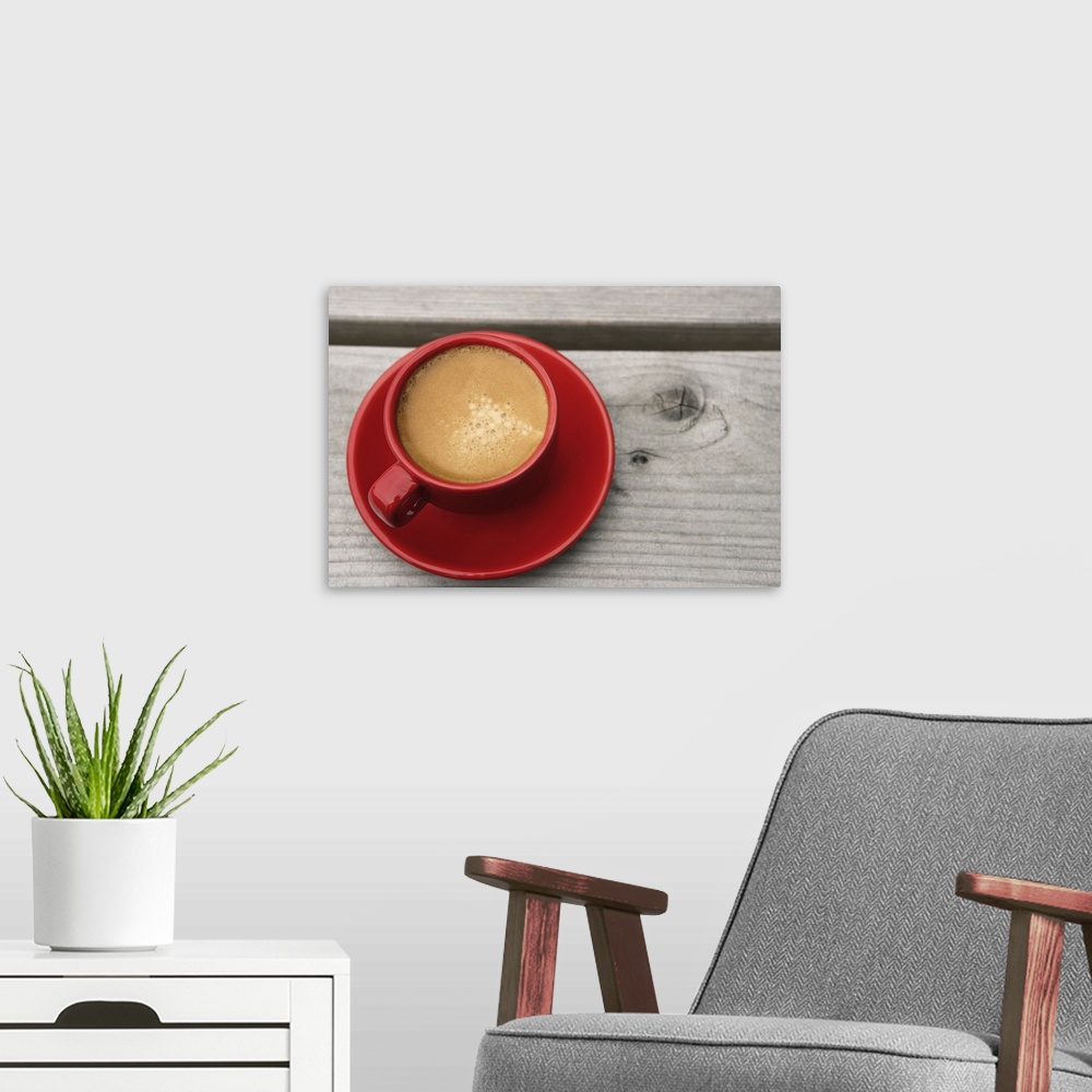 A modern room featuring A bright red cup of espresso coffee on a picnic table outdoors on a summer day.