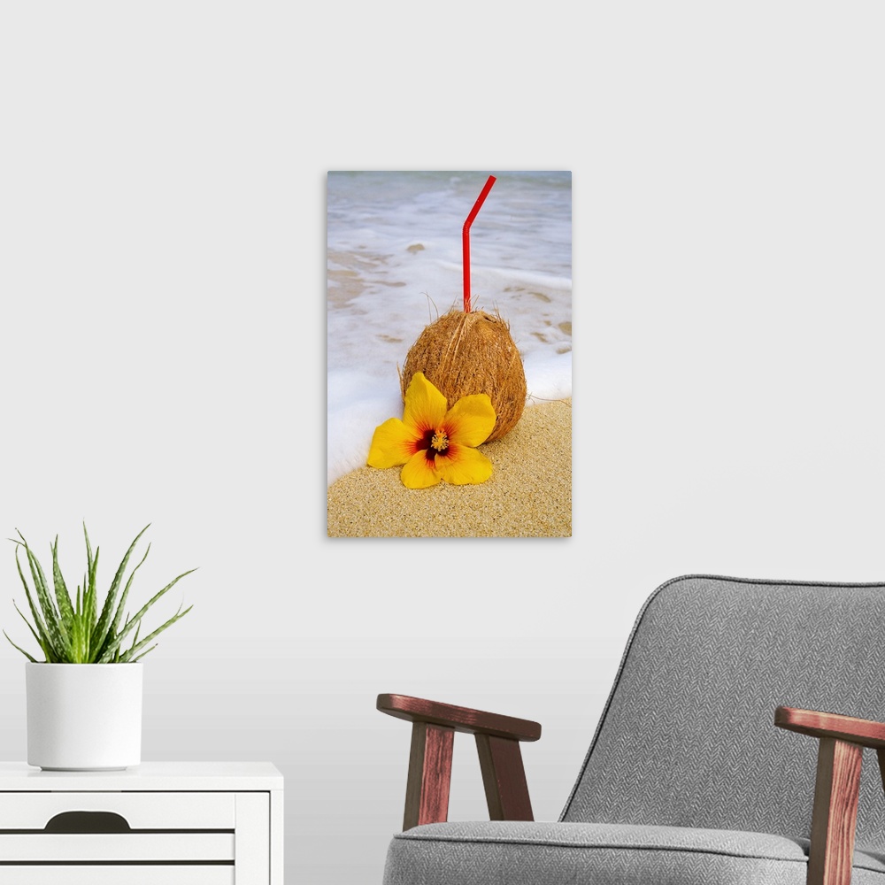 A modern room featuring A coconut drink with straw sticking out and flowers on a tropical beach.