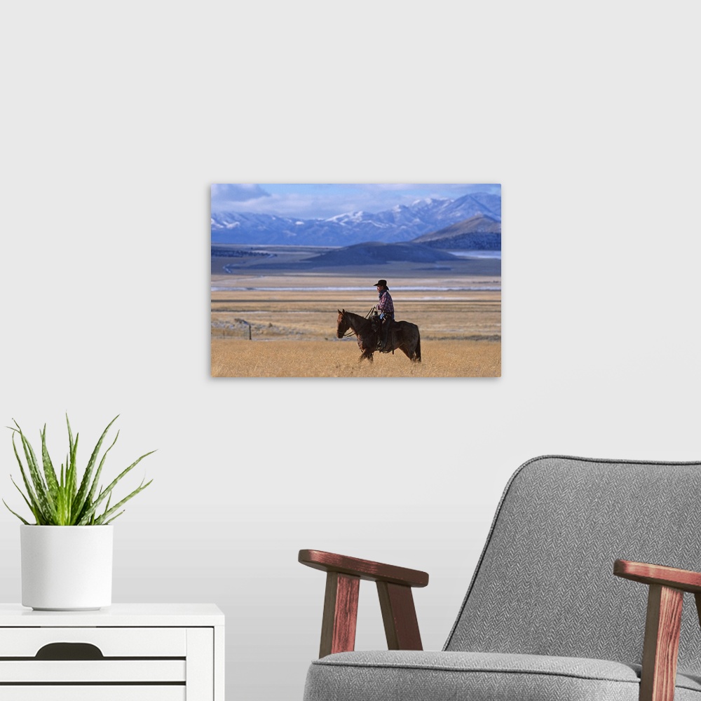 A modern room featuring a horizontal image of a cowboy riding his horse in a yellow field alone