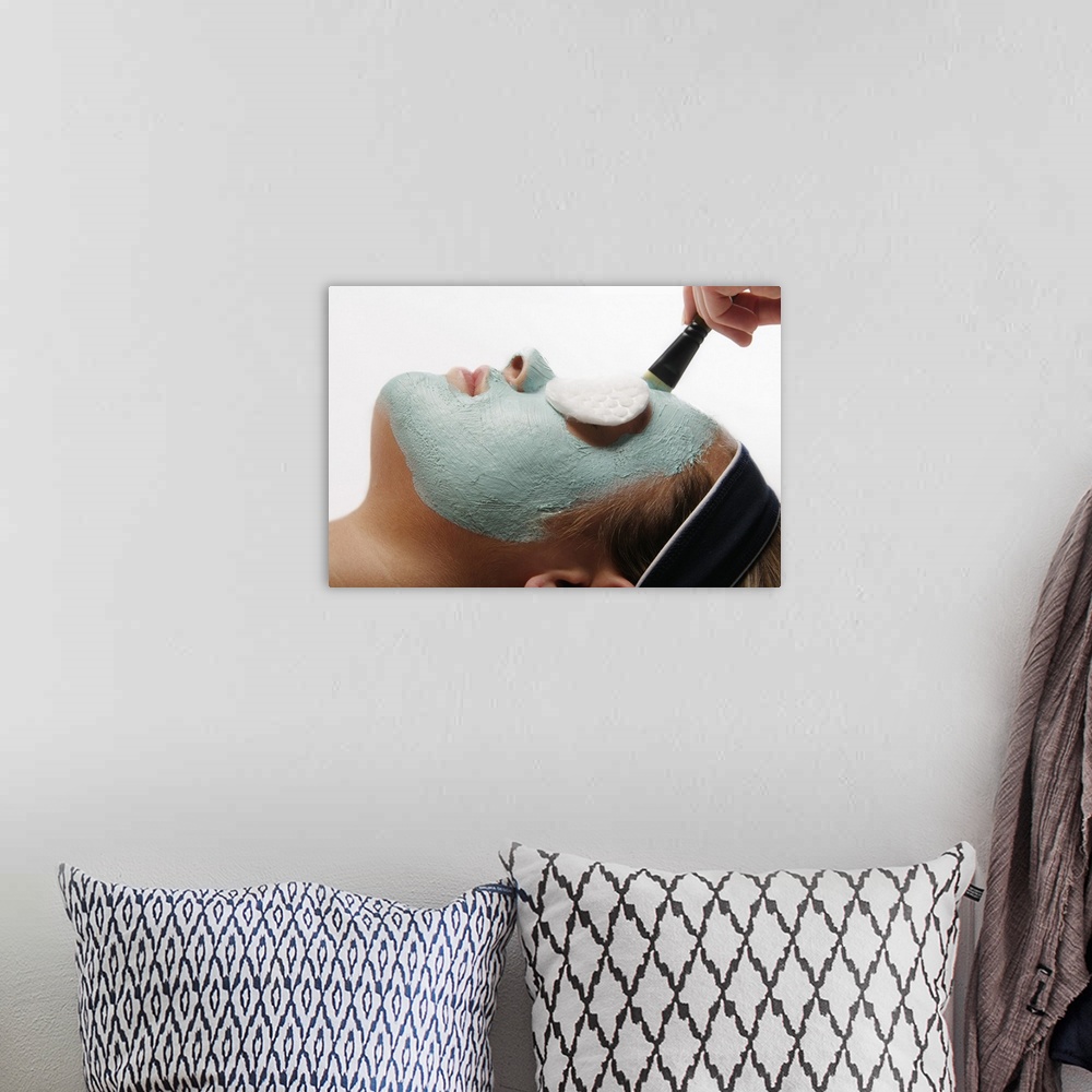 A bohemian room featuring Photograph of woman's face with clay mask and sponge covered eyes.