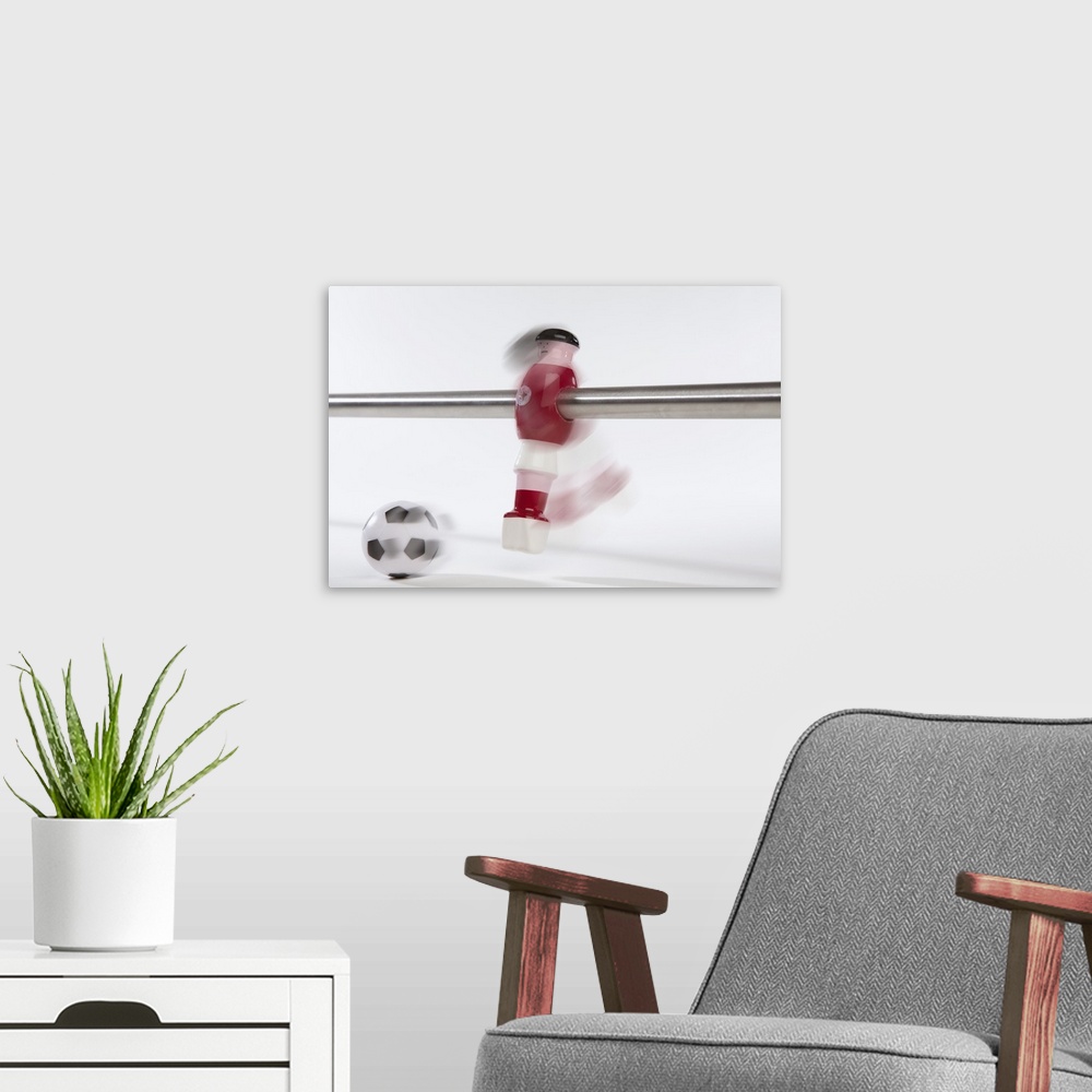 A modern room featuring A foosball figurine kicking a soccer ball, blurred motion