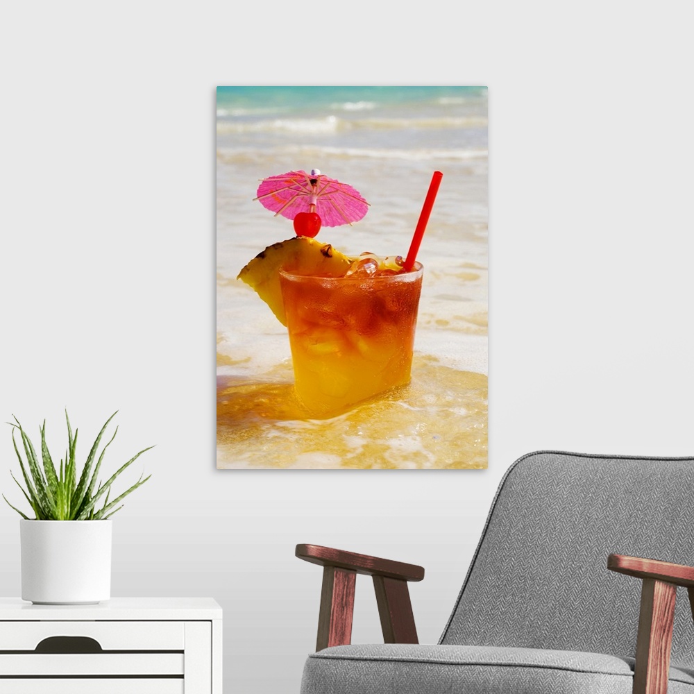 A modern room featuring A mai tai garnished with pinapple and a cherry, sitting in shallow water on the beach.