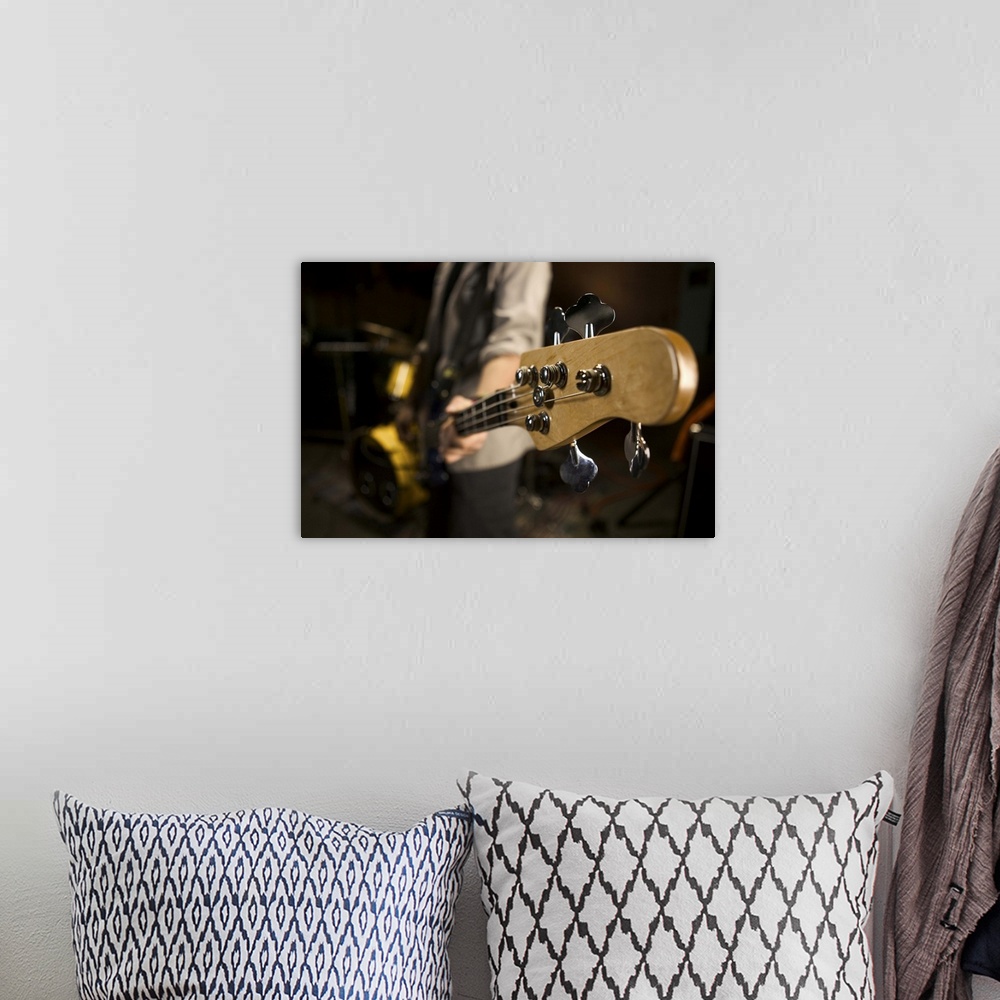 A bohemian room featuring teenage lifestyle shot of a male guitar player as he practices with his rock band