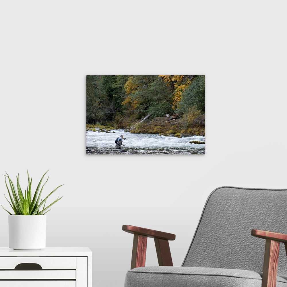A modern room featuring A fisherman tries his luck in the rapids of a quick moving river.