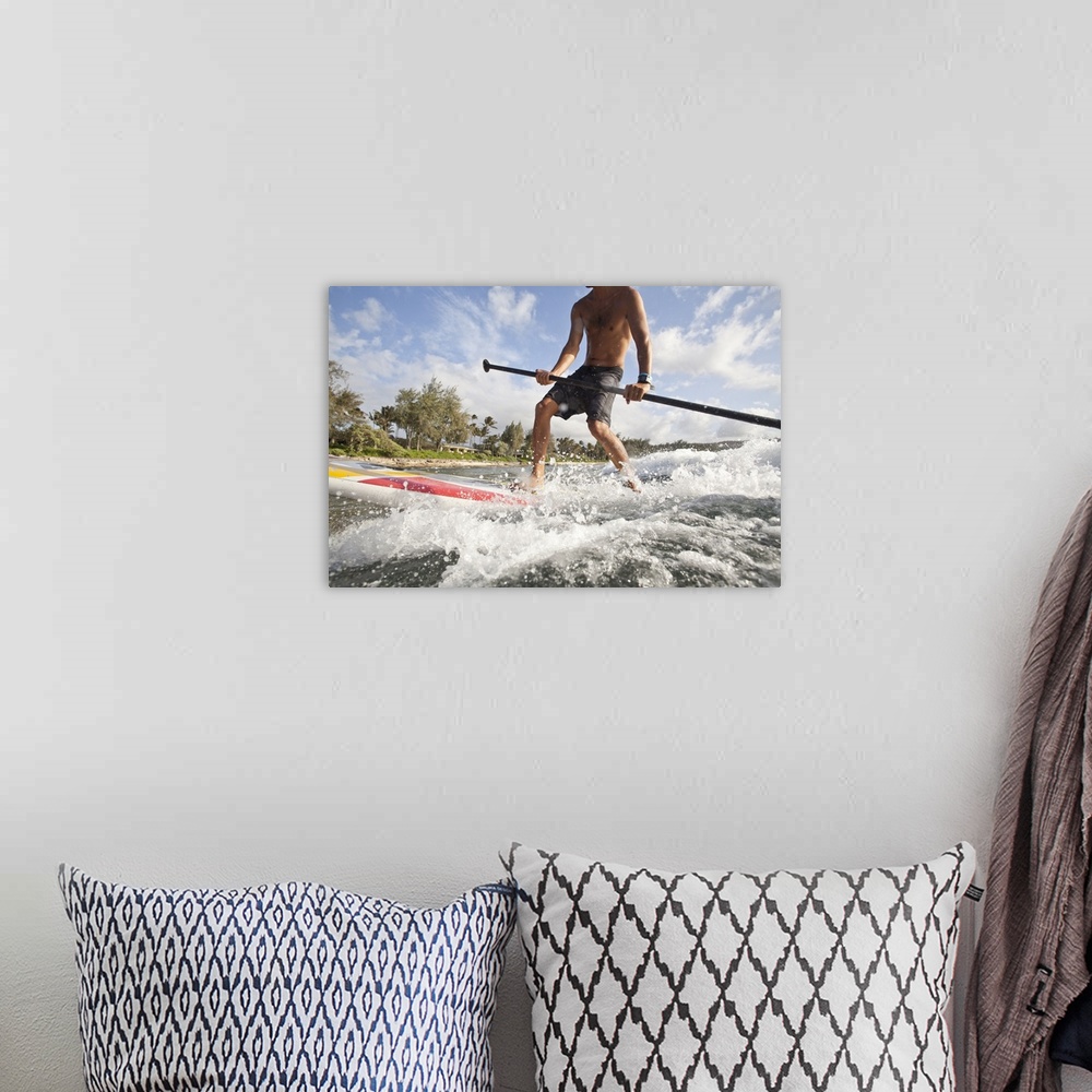 A bohemian room featuring Low angle view of a young man riding an ocean wave on a stand up paddle board