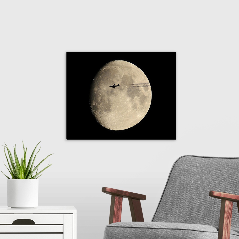 A modern room featuring plane crossing in front of moon.