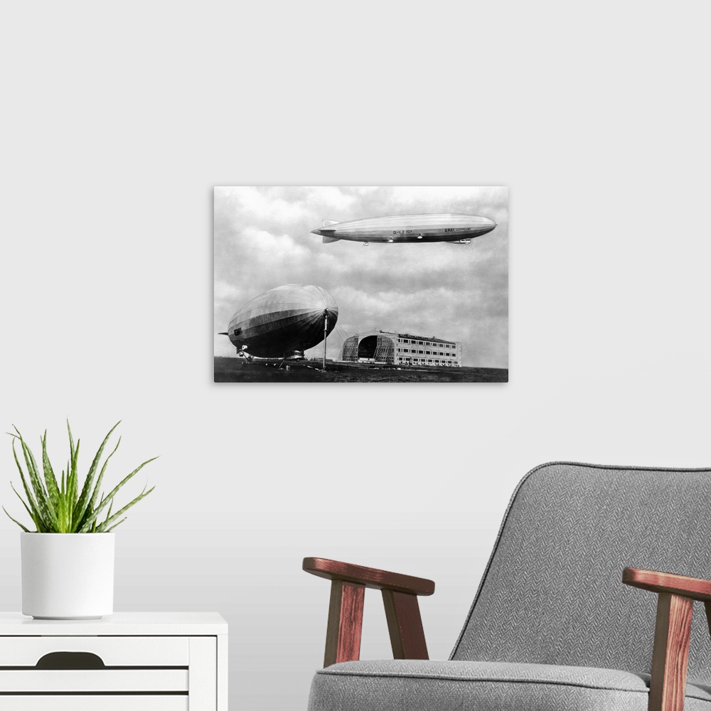 A modern room featuring Airship LZ 127 Graf Zeppelin hovers over airship LZ 126 Los Angeles near a hangar at Lakehurst, N...