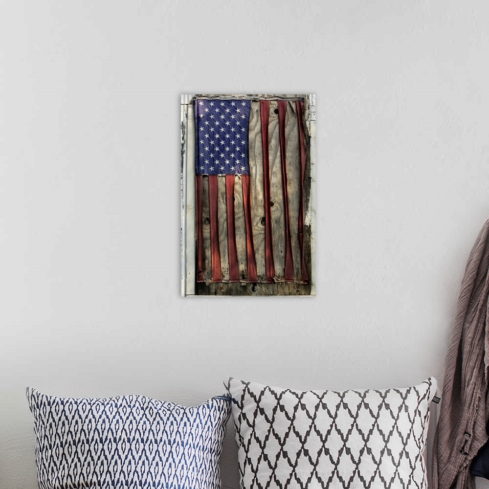 A bohemian room featuring A vertical photograph of a flag nailed to a board that has become so distressed and weather beate...