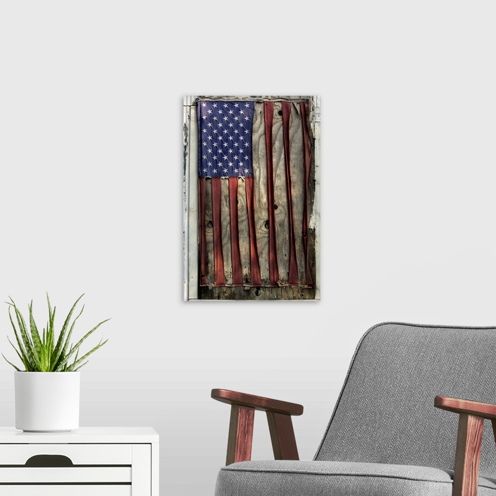 A modern room featuring A vertical photograph of a flag nailed to a board that has become so distressed and weather beate...