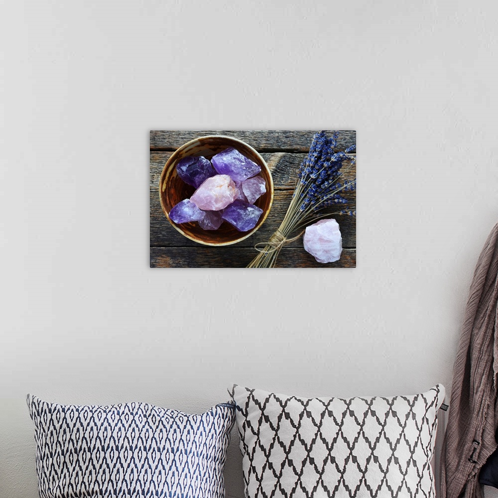 A bohemian room featuring A table top image of a pottery bowl with large rose quartz and amethyst crystal with dried lavend...