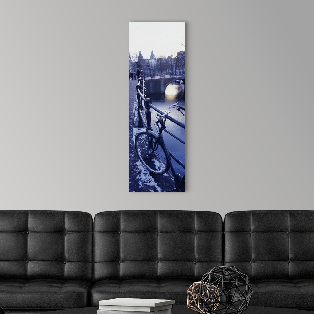 A modern room featuring Amsterdam, Holland - bicycle standing at railings on canal bank