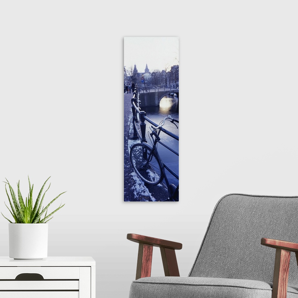 A modern room featuring Amsterdam, Holland - bicycle standing at railings on canal bank