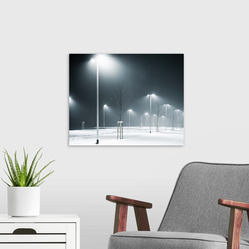 A modern room featuring An empty, snow-covered parking lot at night time.