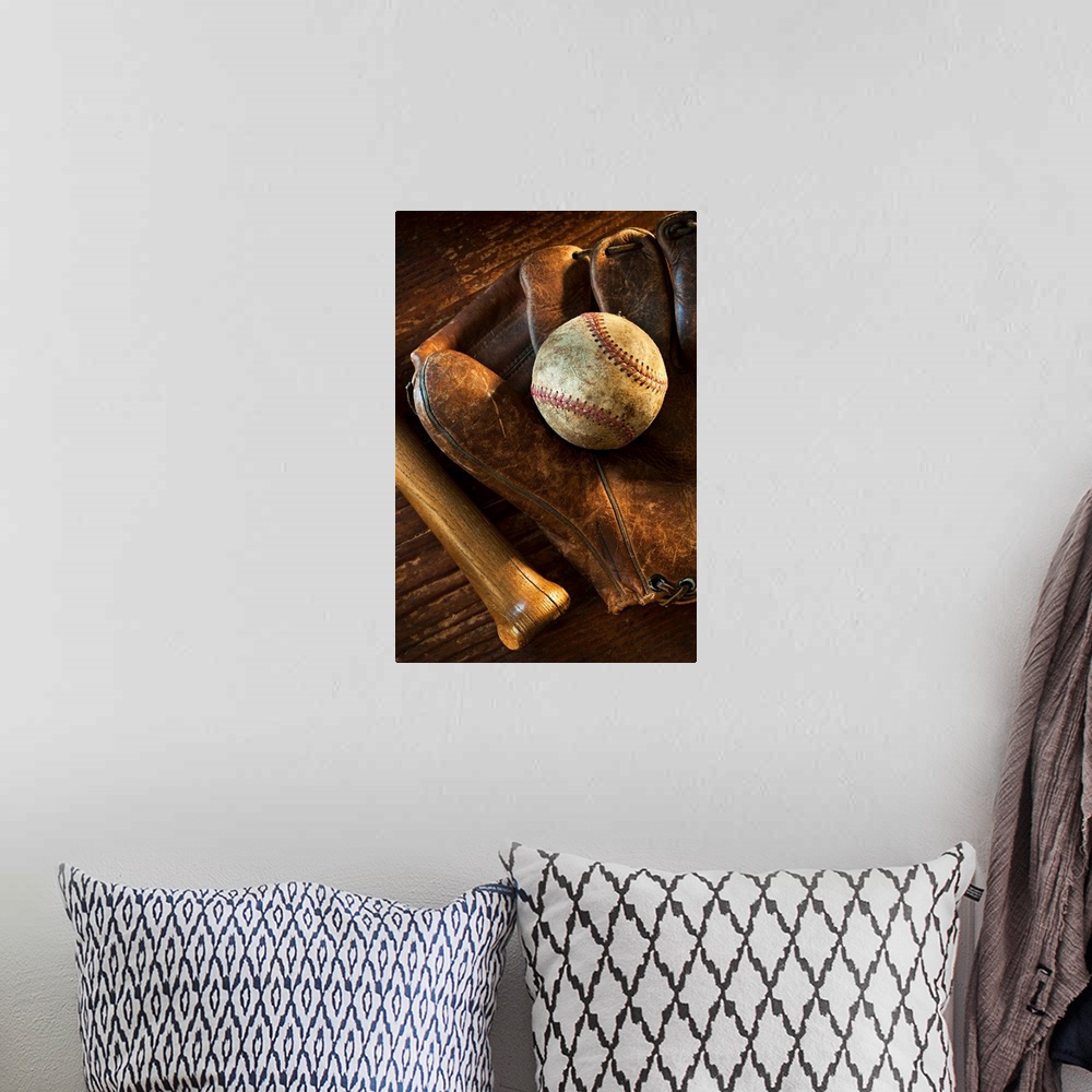 A bohemian room featuring Wall docor of a worn baseball laying on top of an old baseball mit with a wooden bat next to it.