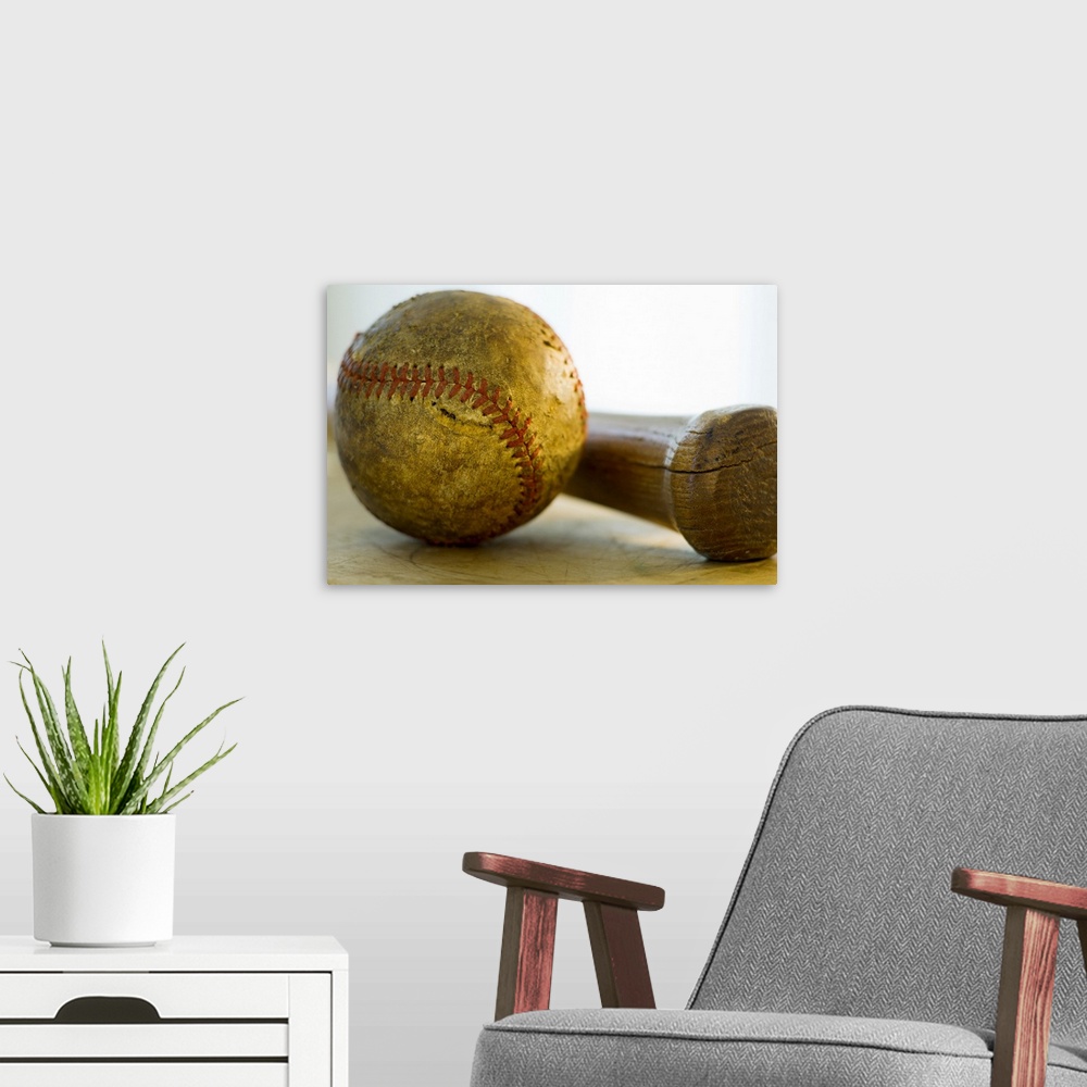 A modern room featuring Huge photograph focuses on a stitched ball of worn cowhide sitting next to a wooden hitting instr...