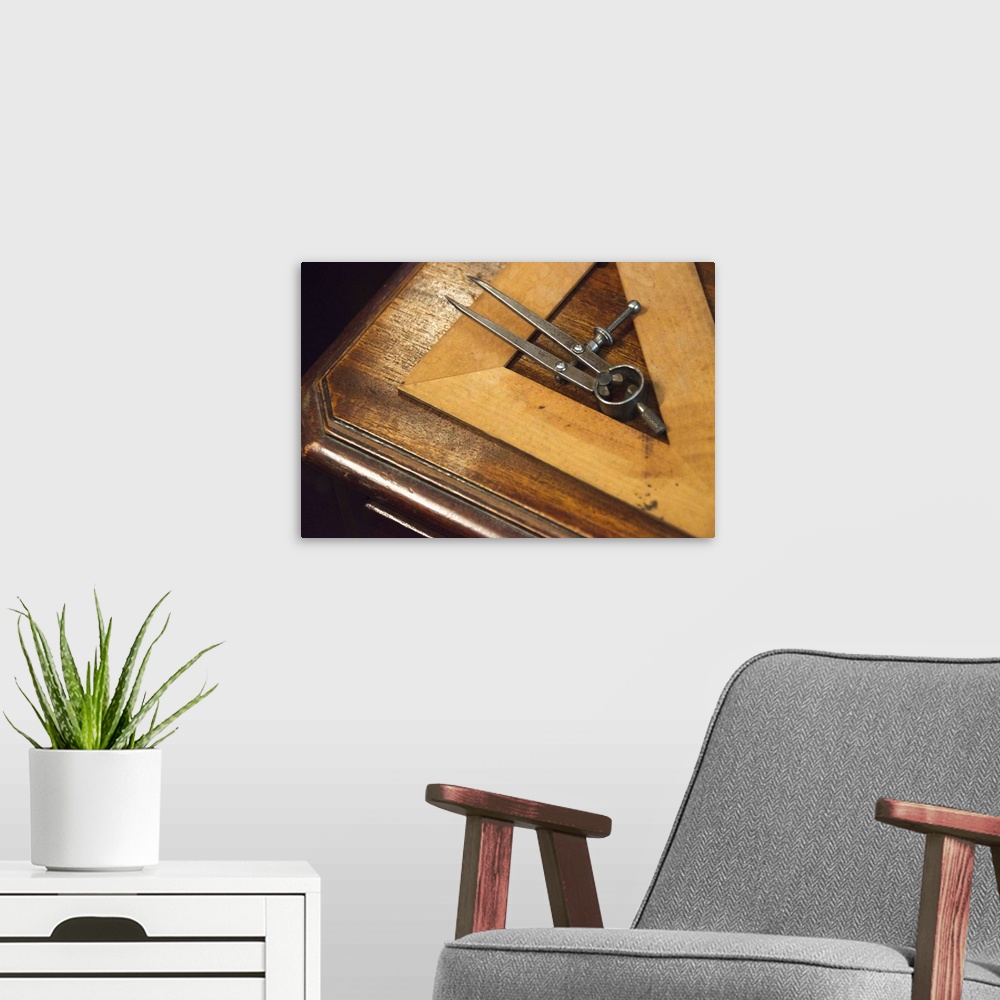 A modern room featuring Antique set square and pair of compasses on wooden table