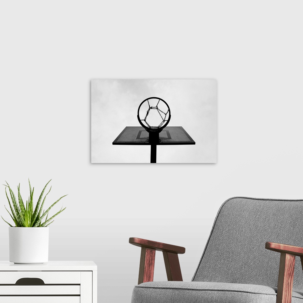 A modern room featuring This is a monochromatic, horizontal photograph taken from below an outdoor basketball hoop.